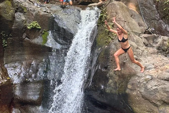 Hikers cooling off beneath the cascading Tamanique Waterfalls on a Tamanique waterfalls tour near El Tunco, El Salvador